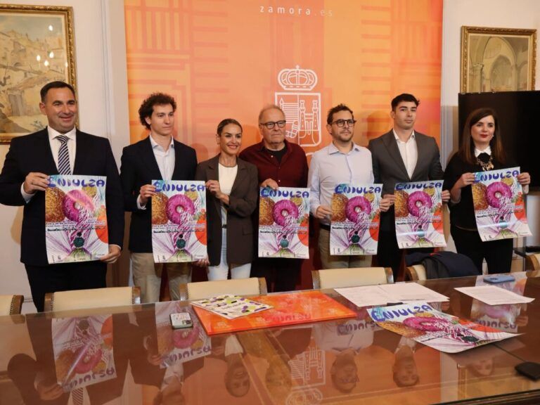 Siete personas sostienen carteles de ENDULZA frente a un fondo naranja con un escudo