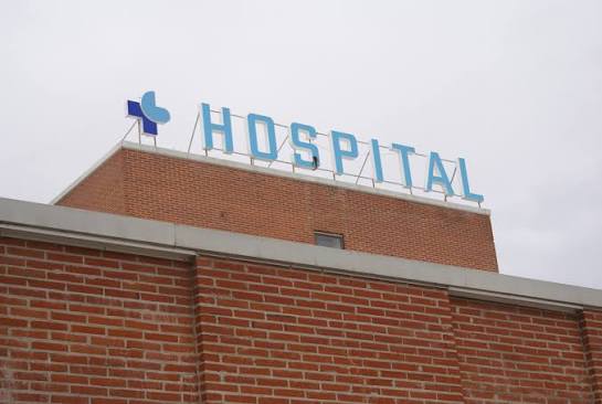 Rótulo azul con la palabra hospital sobre una fachada de ladrillo