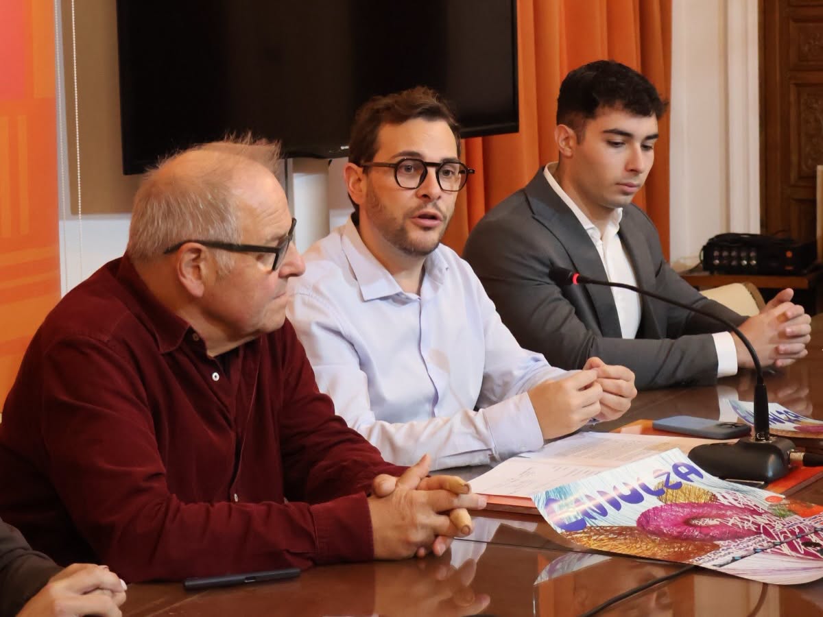 Tres hombres sentados ante una mesa con documentos y un cartel de ENDULZA.