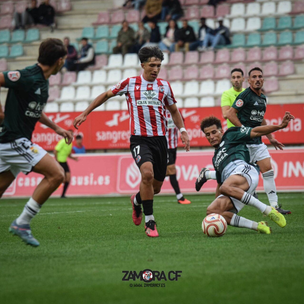Futbolistas disputan el balón durante un partido en un campo de césped.